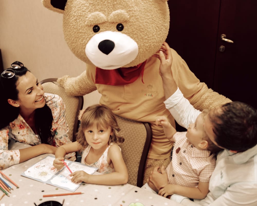 a group of children sitting next to a person in a garment