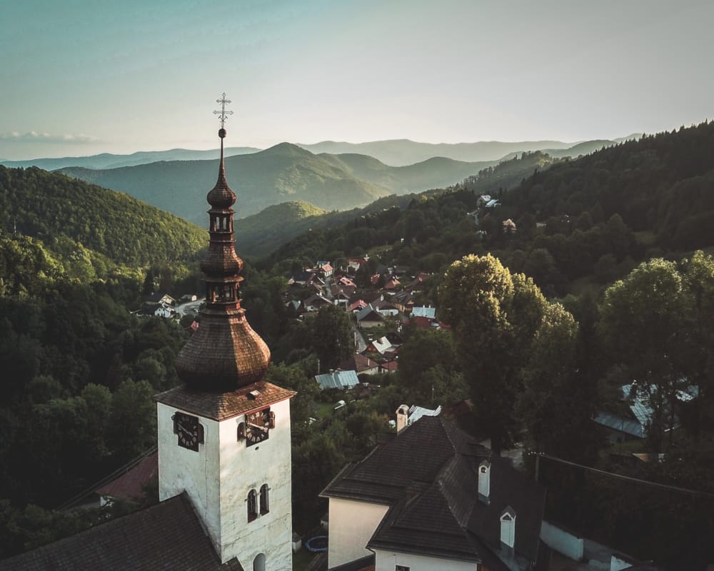 a tall tower with a cross on top surrounded by trees