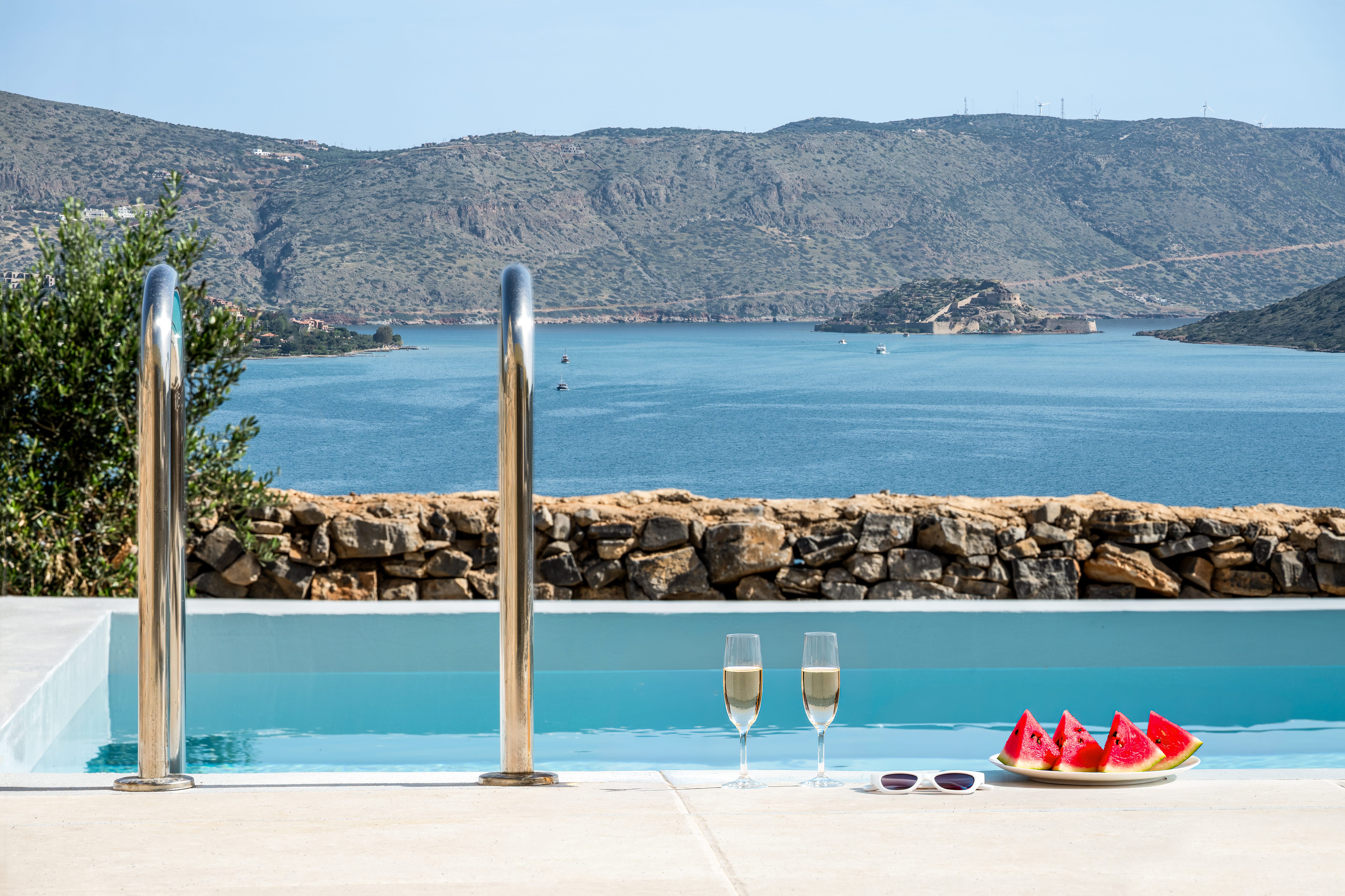 a pool with a view of watermelon and glasses of wine