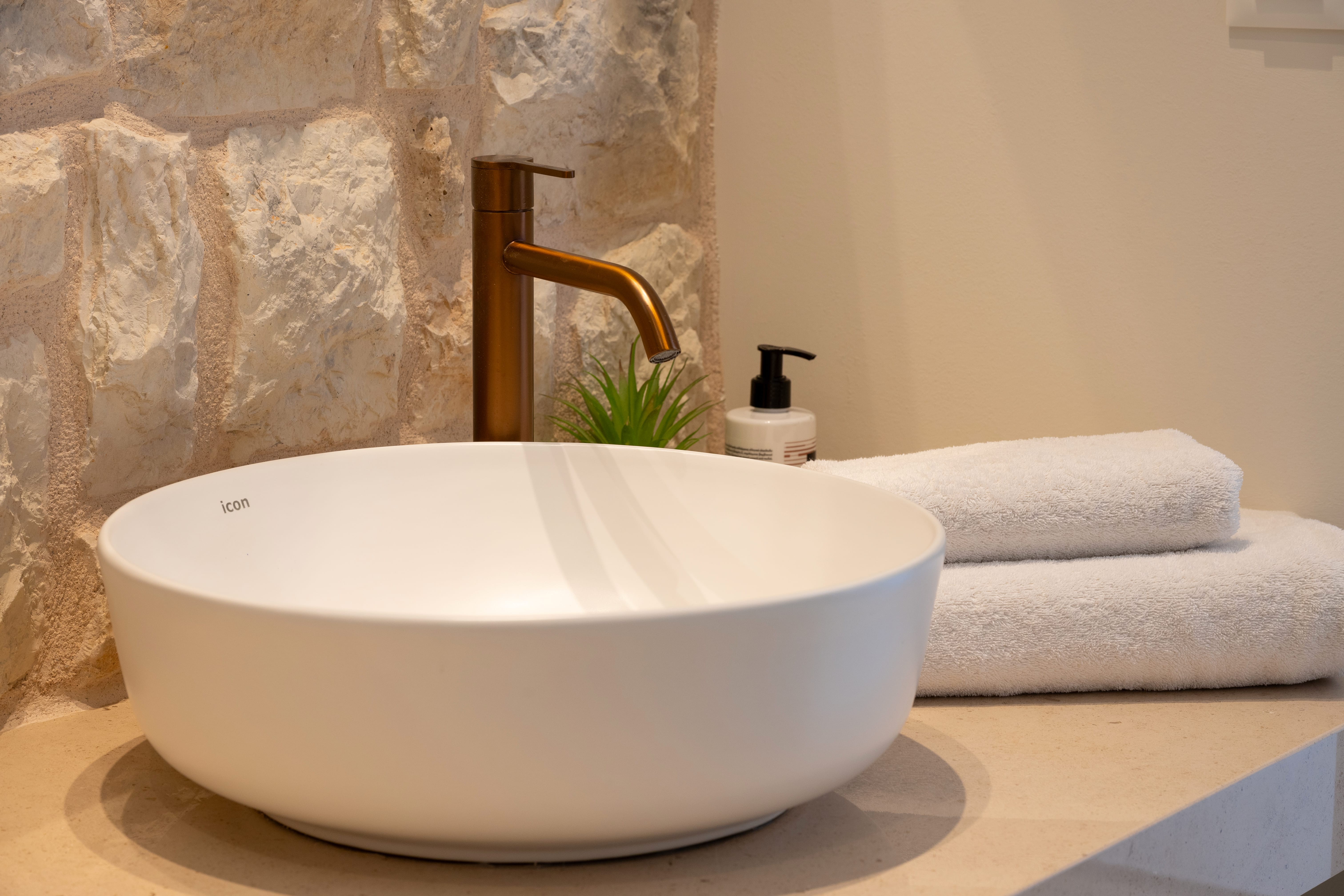 a white sink with a gold faucet and towels