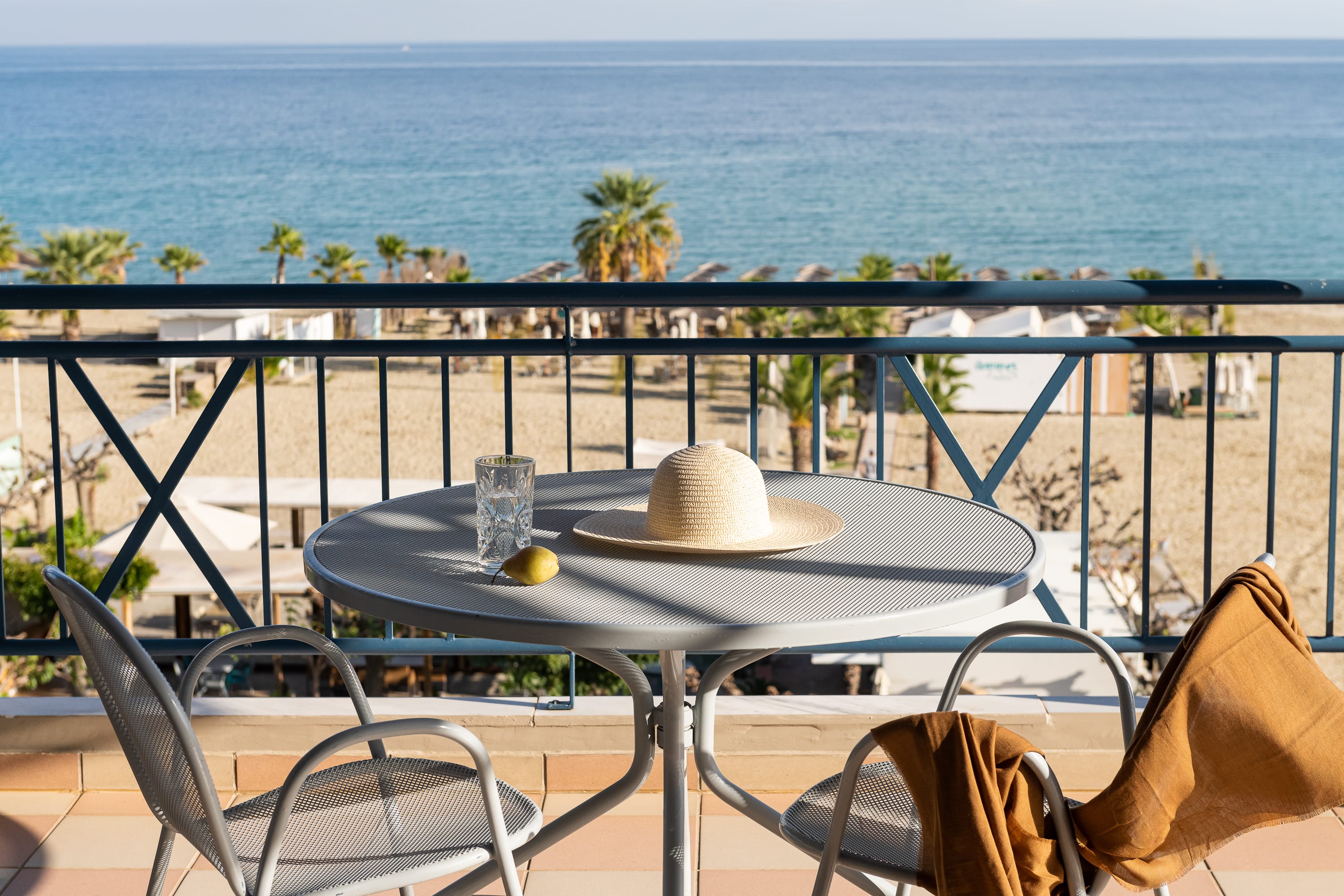 a table with a hat and chairs by a body of water