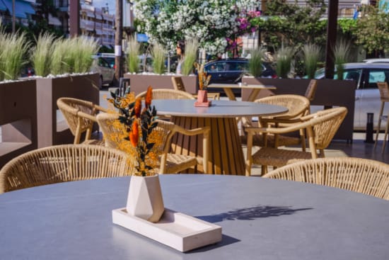 a table with chairs and a vase with yellow flowers on it