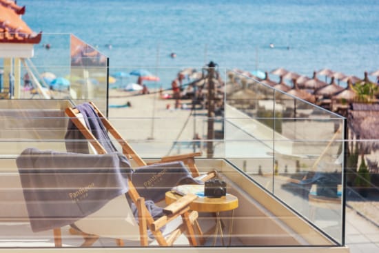 a deck with chairs and tables by a beach