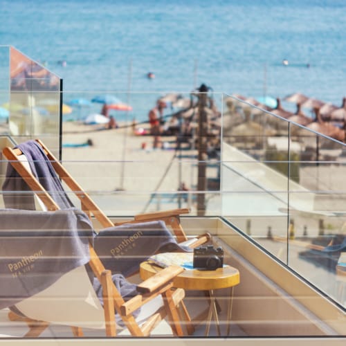 a deck with chairs and tables by a beach