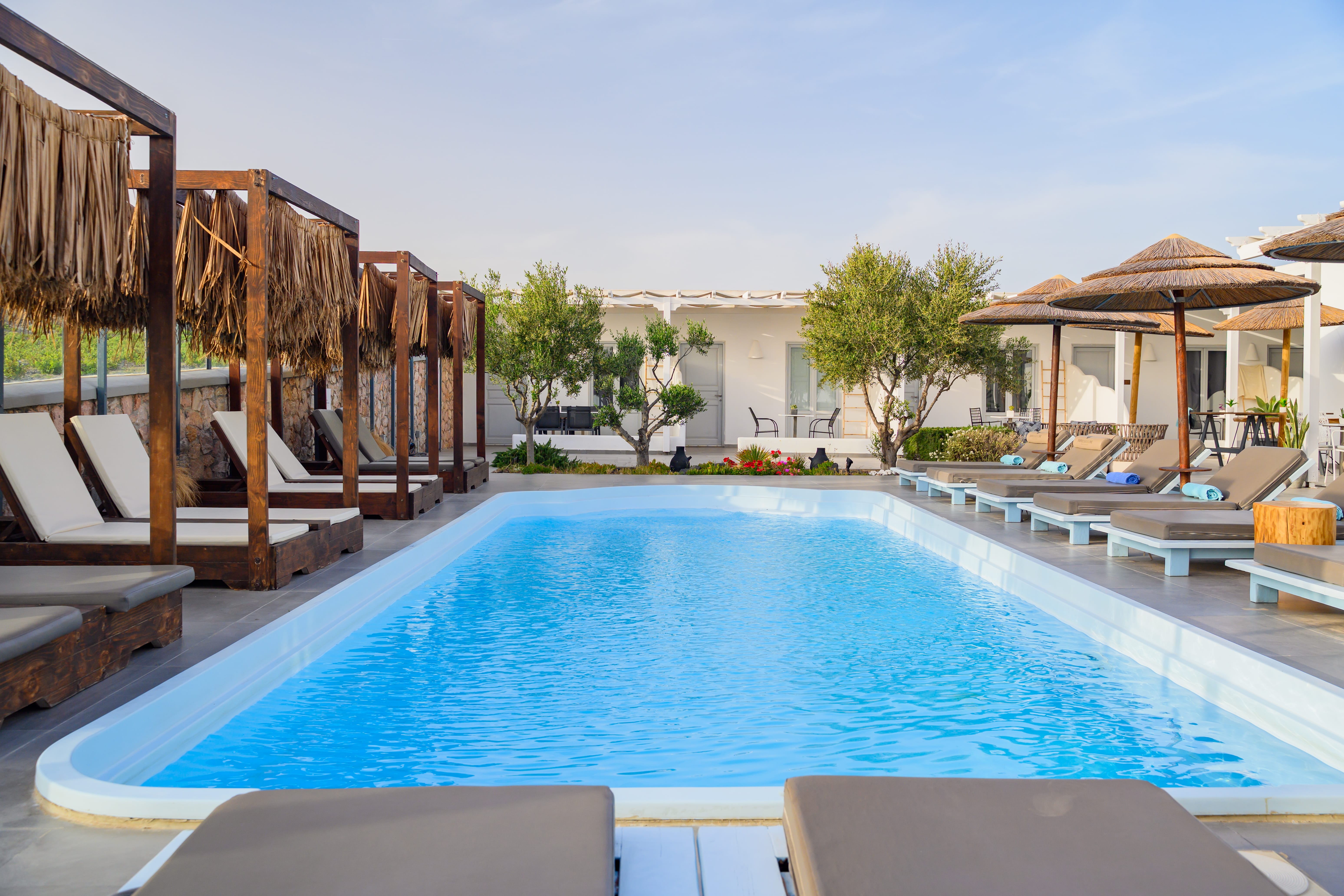 a swimming pool with lounge chairs and umbrellas by it