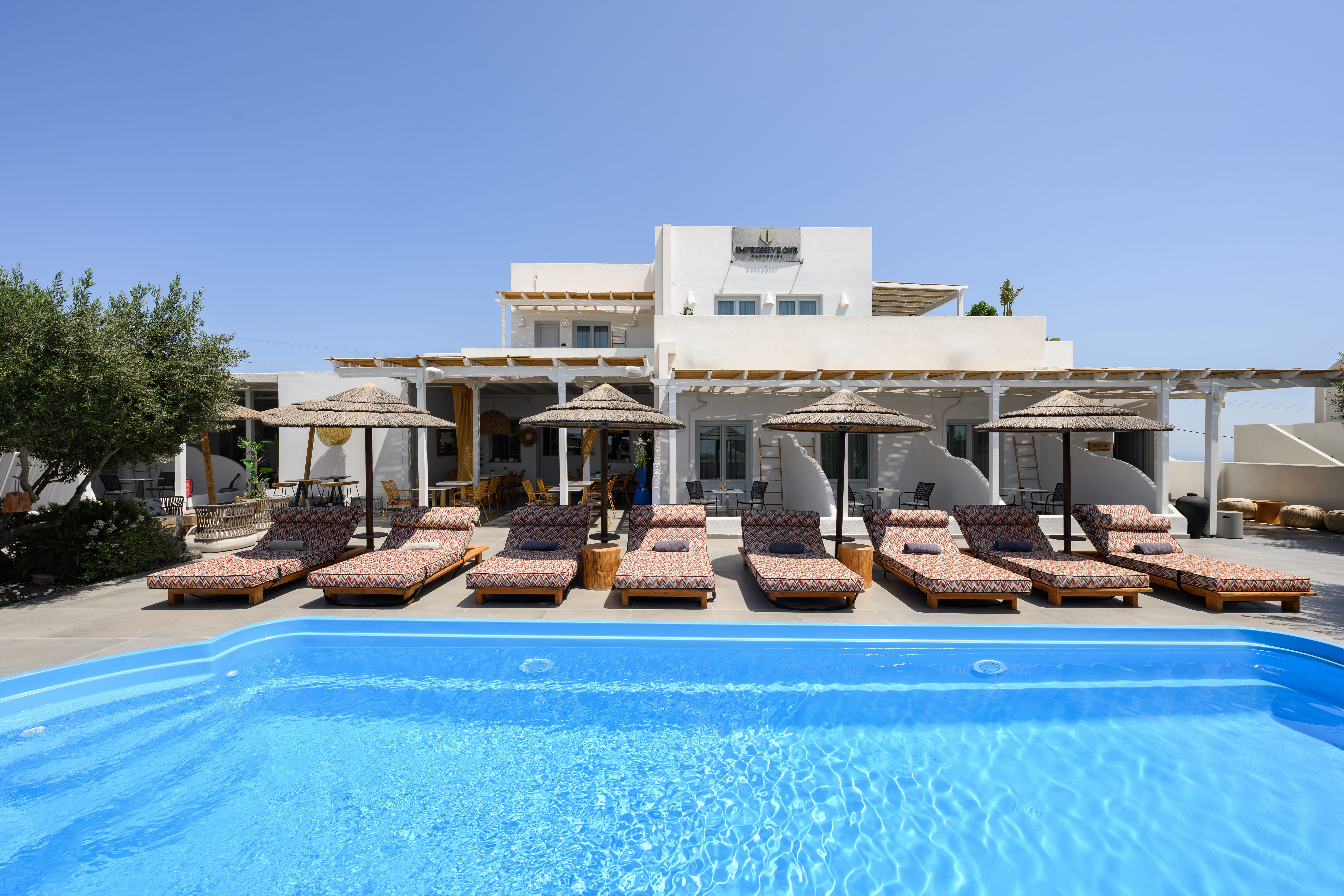 a pool with lounge chairs and umbrellas by a building