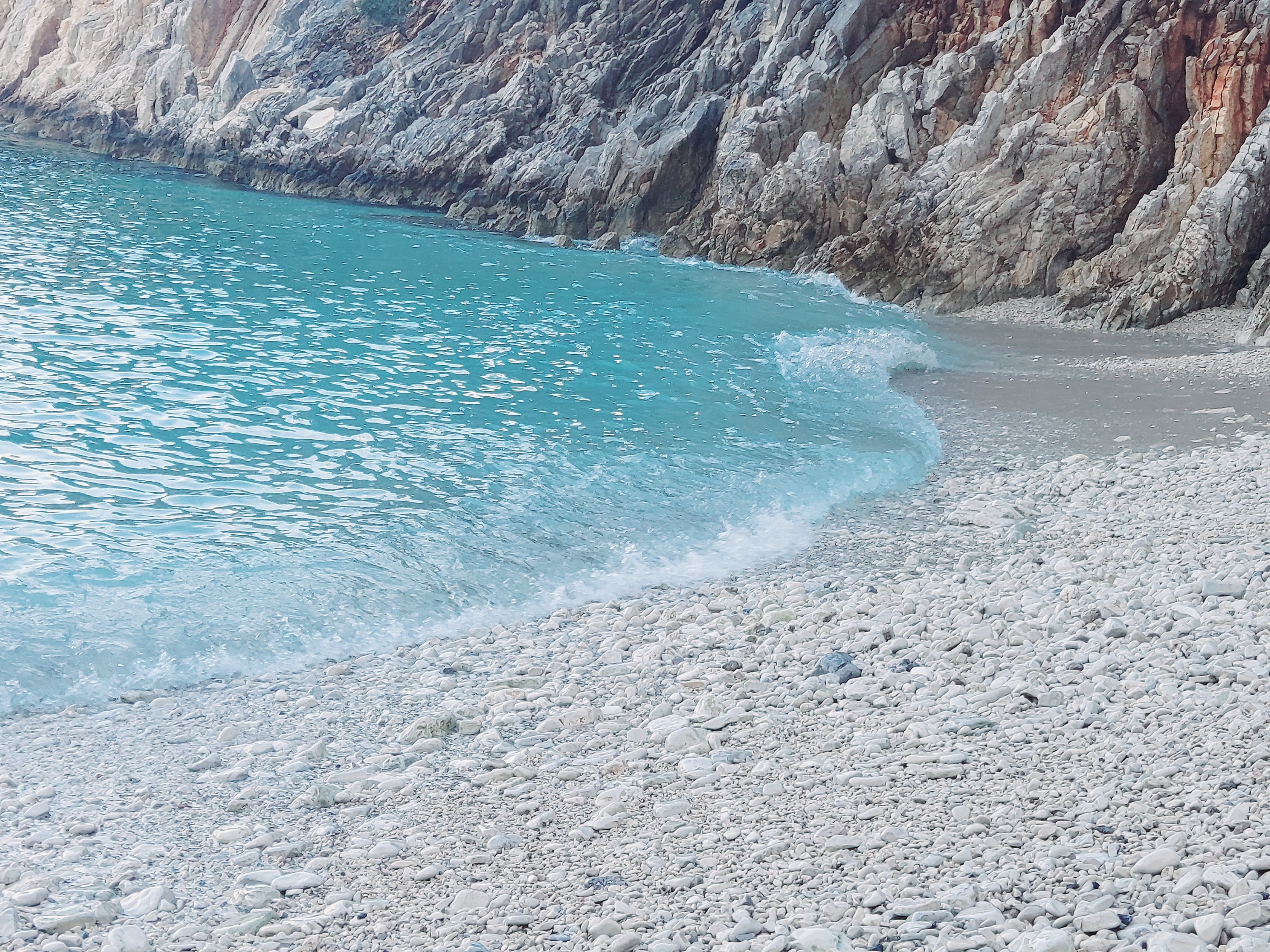 a body of water with a rocky cliff in the background