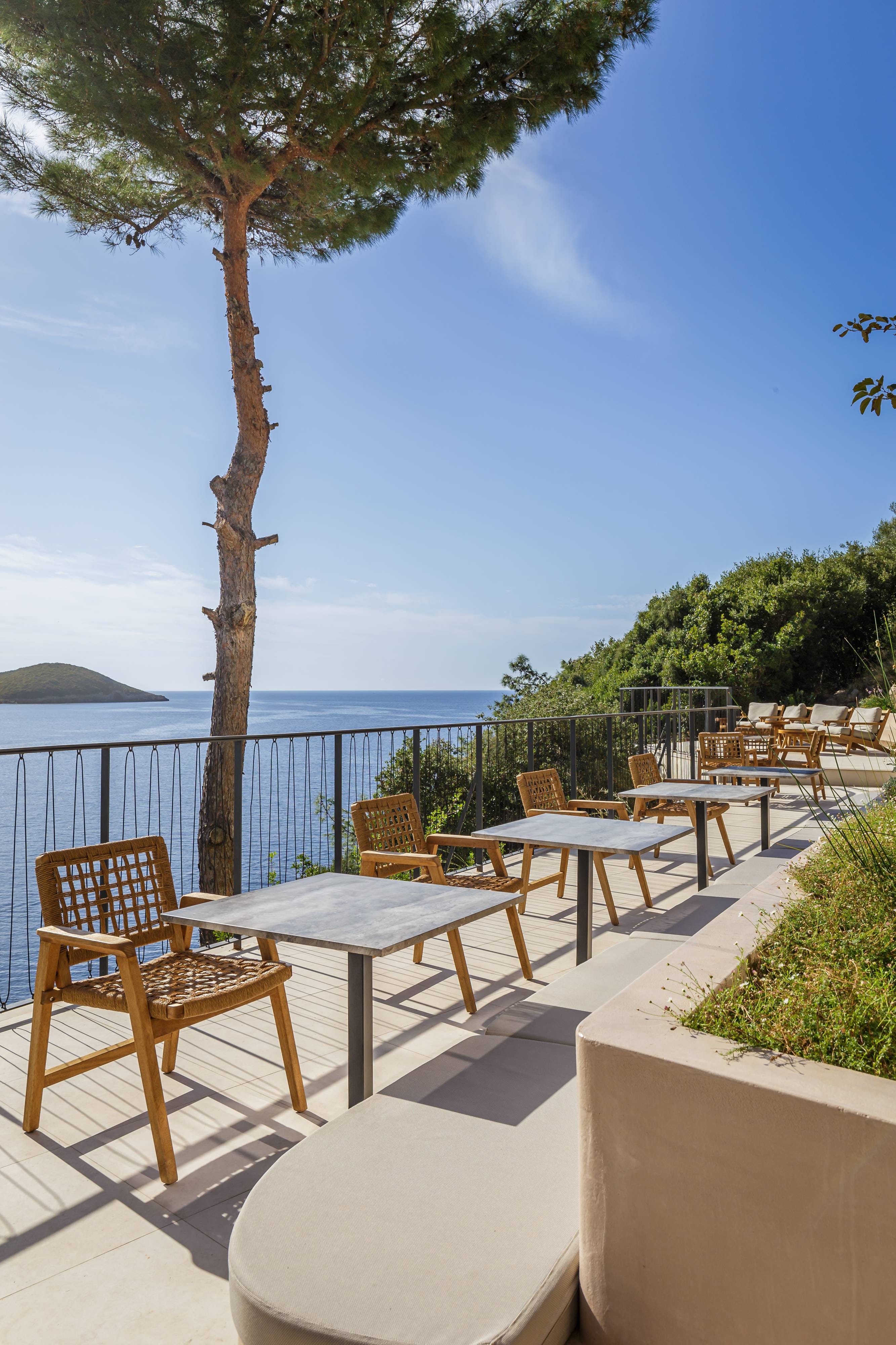 a deck with tables and chairs on it by a body of water