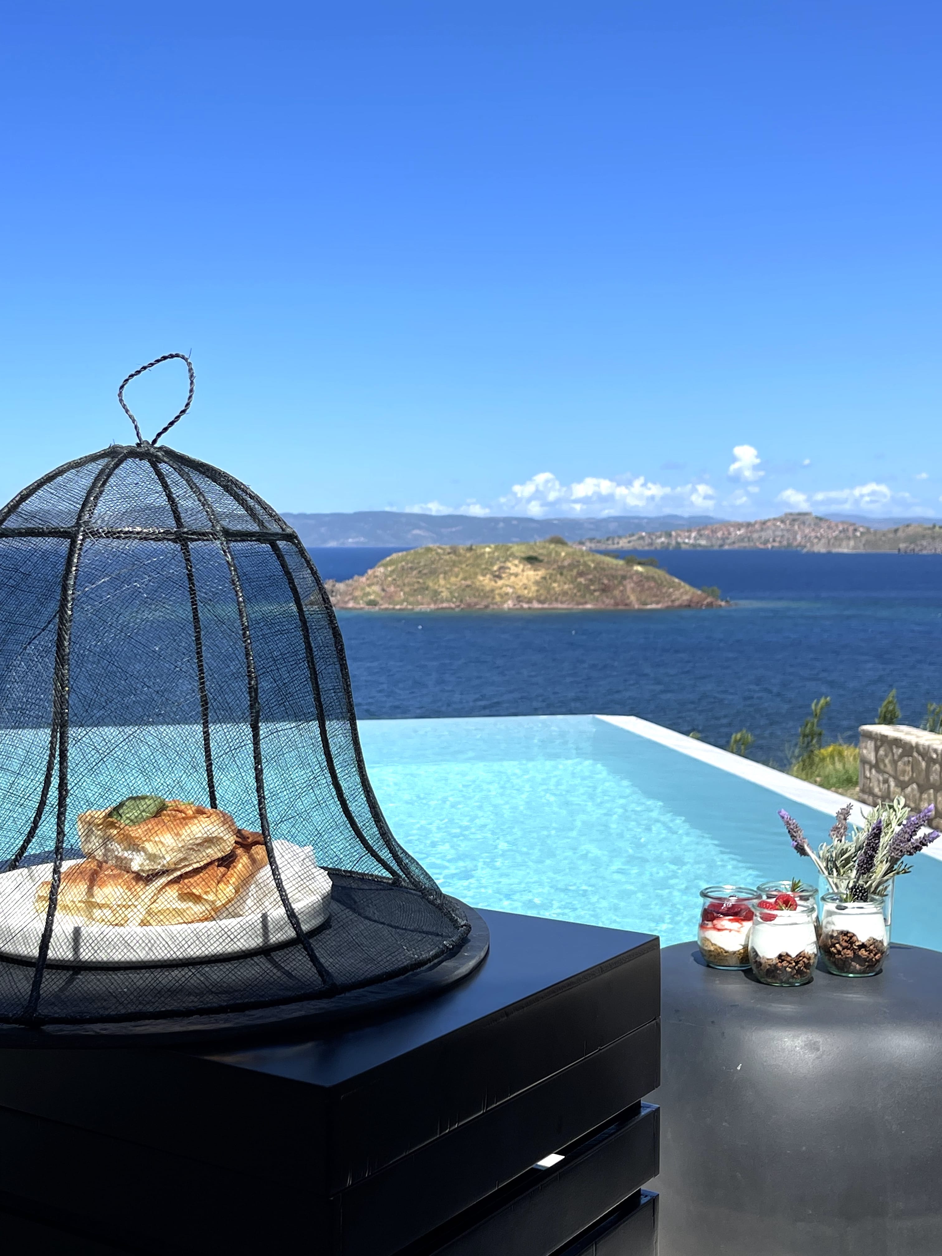 a table with a plate of food and a body of water in the background