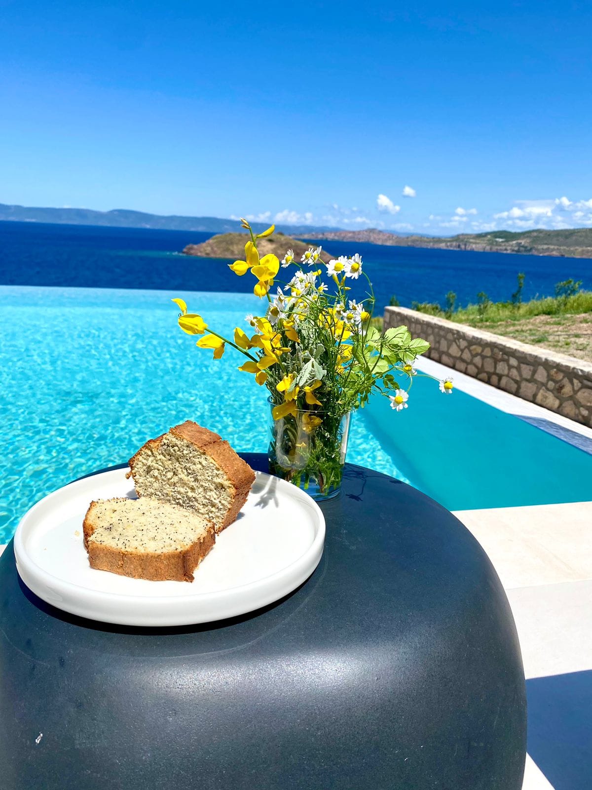 a vase of flowers sits on a table next to a plate of food
