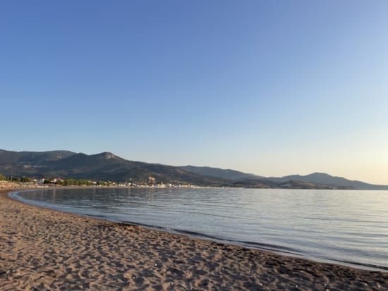 a beach with a body of water and mountains in the background