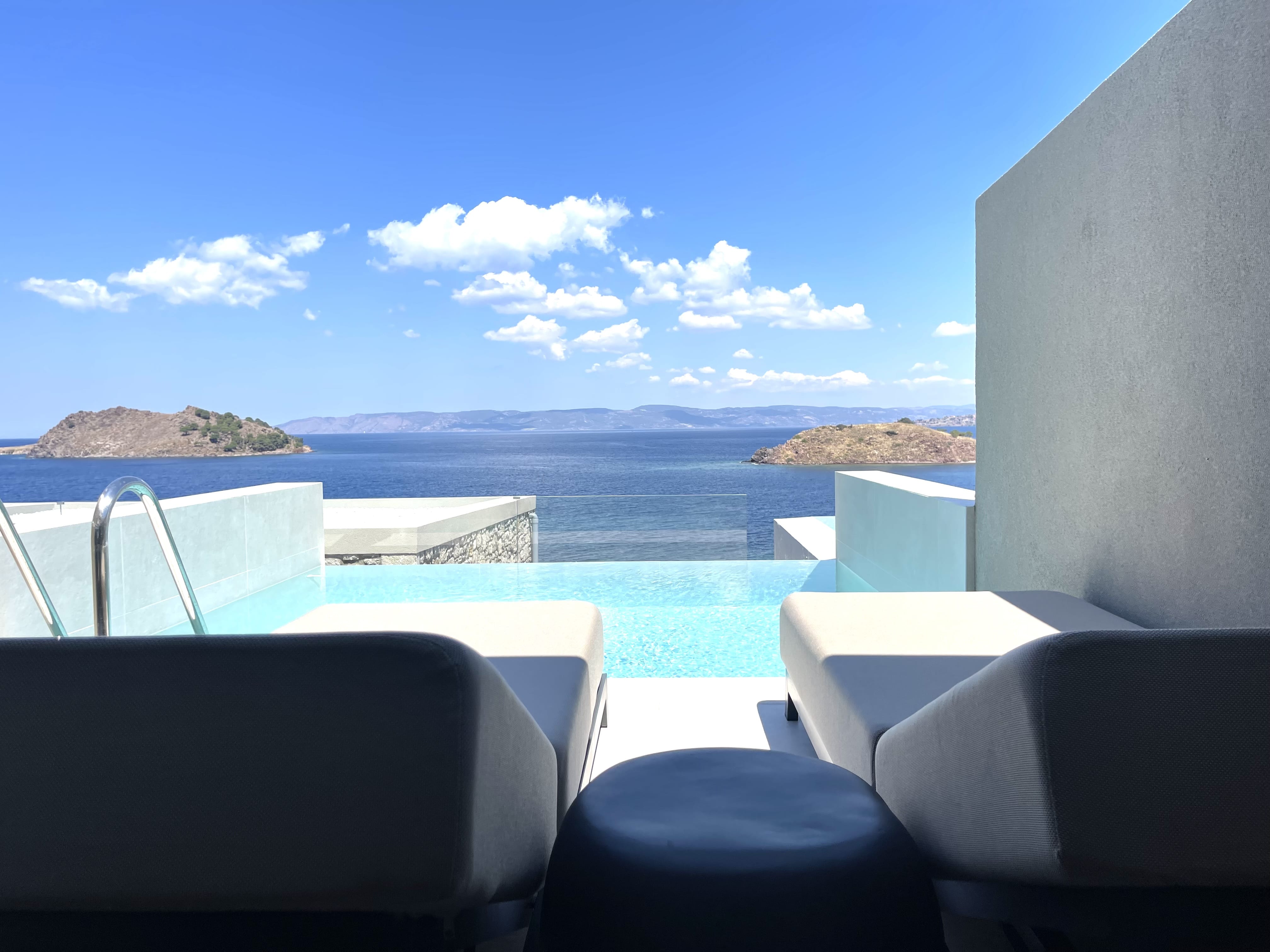 a pool with chairs and a view of the ocean