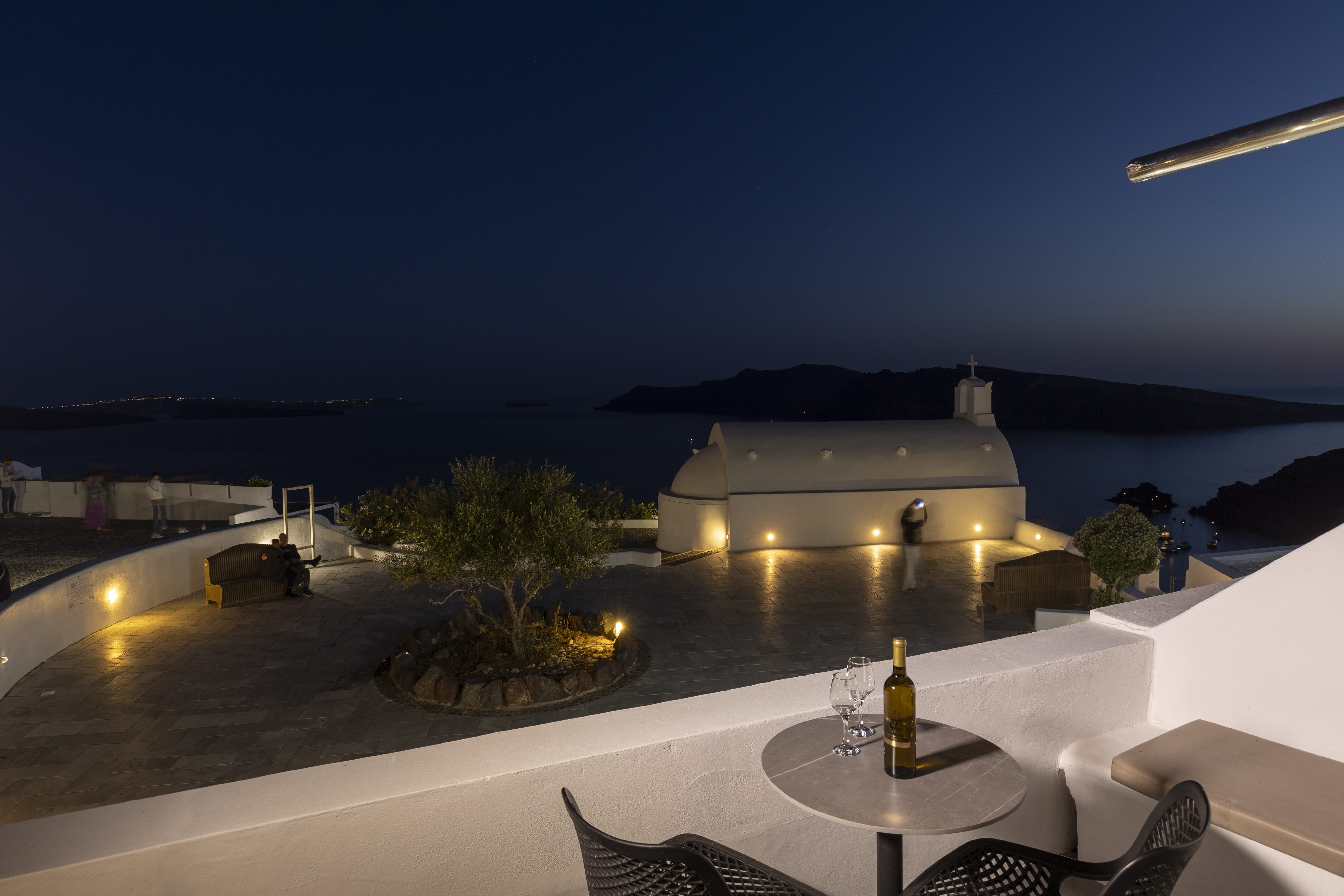 a rooftop with a bottle of wine and a table with a glass of wine on it