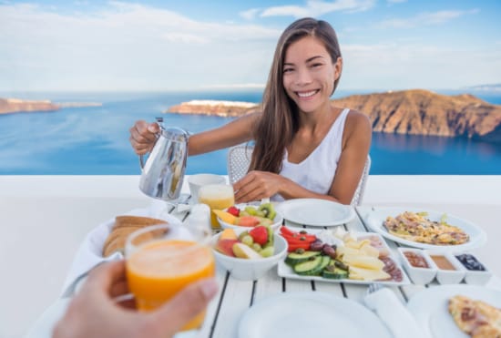 a woman sitting at a table with food and drinks