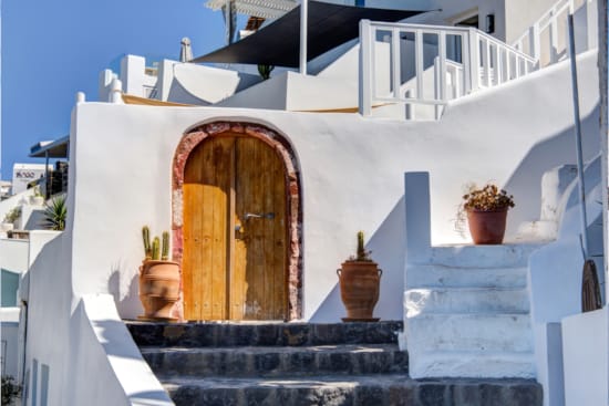 a white building with a door and potted plants on the roof