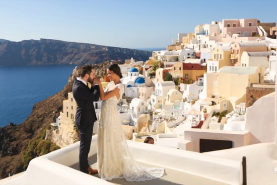 a man and woman kissing on a rooftop overlooking a city