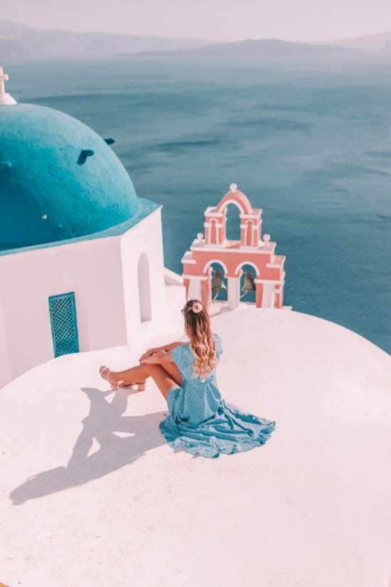 a person in a blue dress lying on a white surface next to a building with a red tower