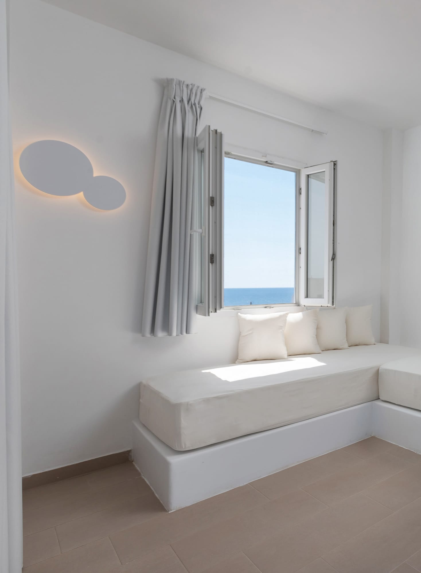 a white room with a white couch and a window