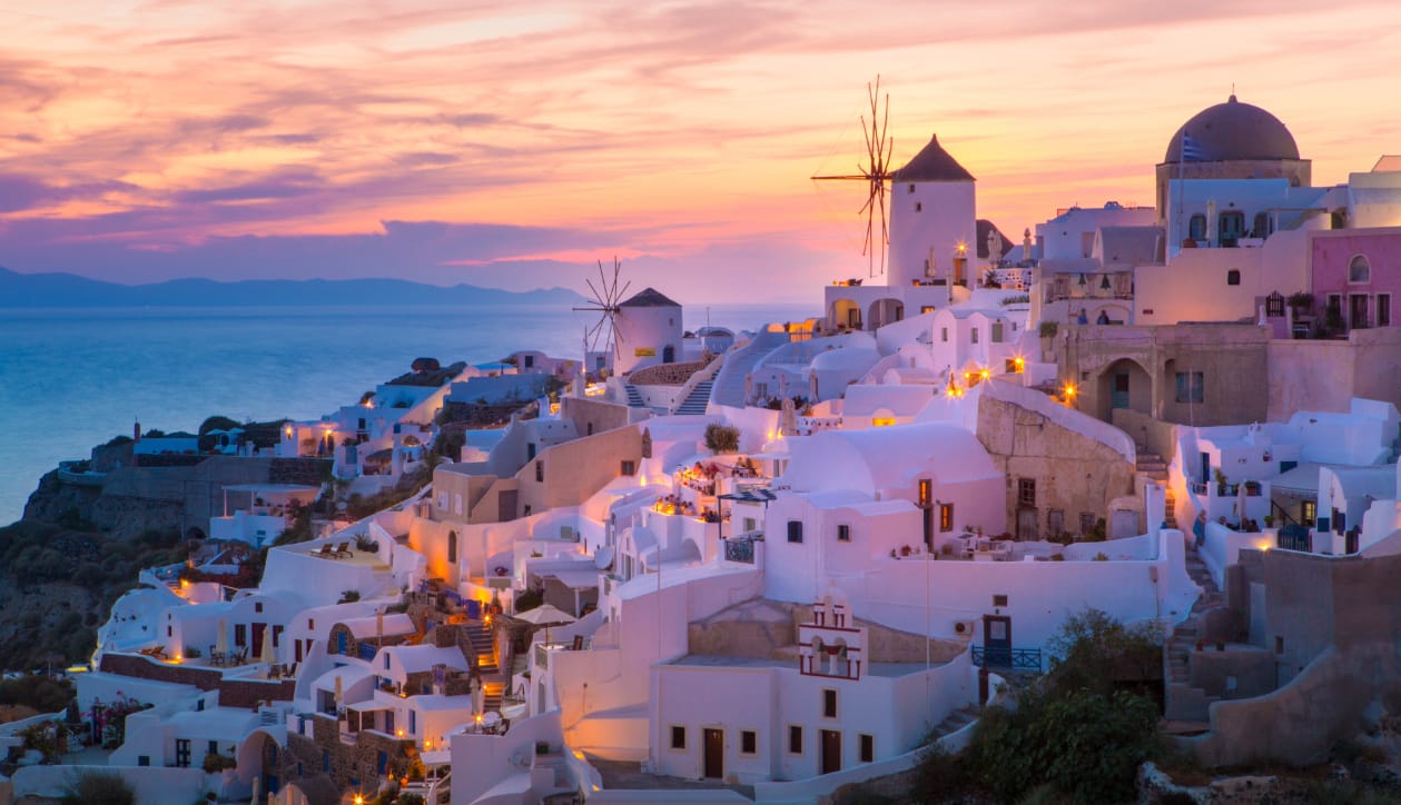 a city with white buildings and a body of water in the background