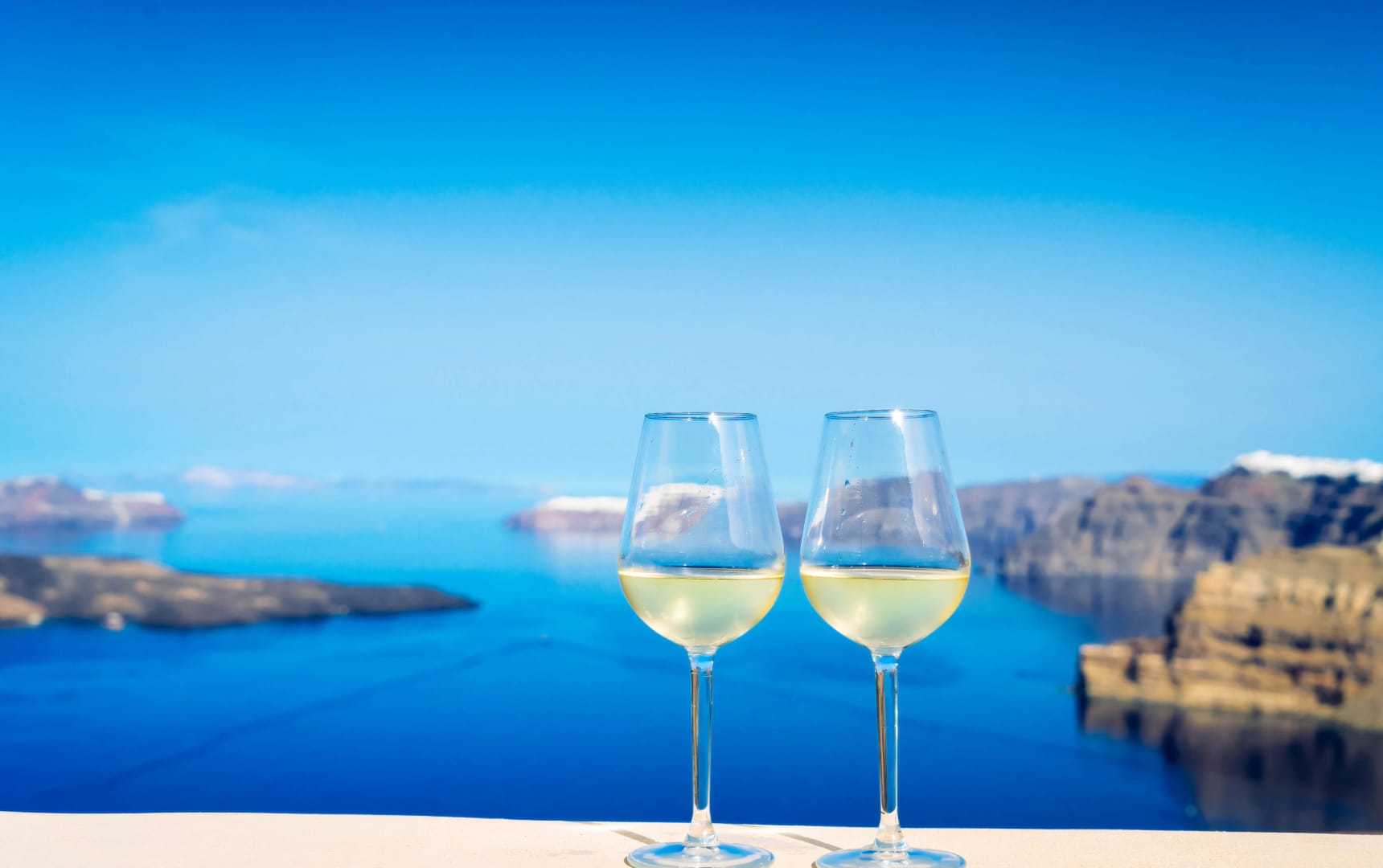 a couple of wine glasses on a beach