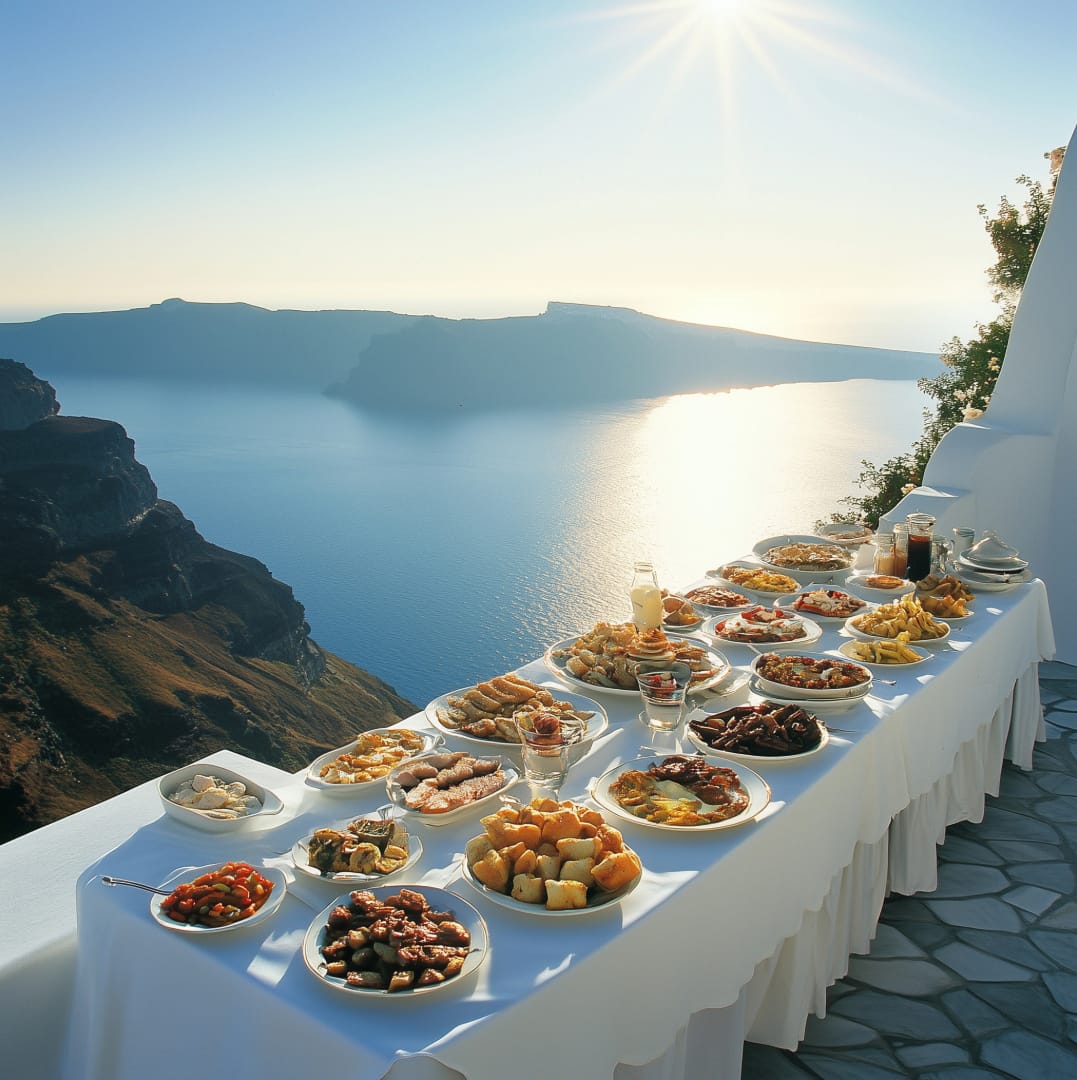 a table with food on it with Santorini in the background