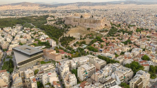 Aerial view of the Acropolis, featuring the Parthenon, amidst the urban landscape of central Athens, near Kyria Boutique House in Plaka.