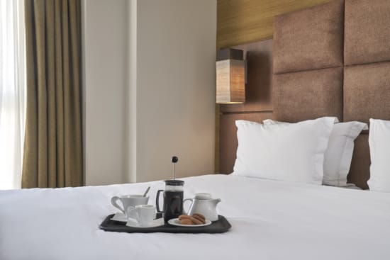 a bed with a white bed spread and a white bed with a white pillow and a black coffee