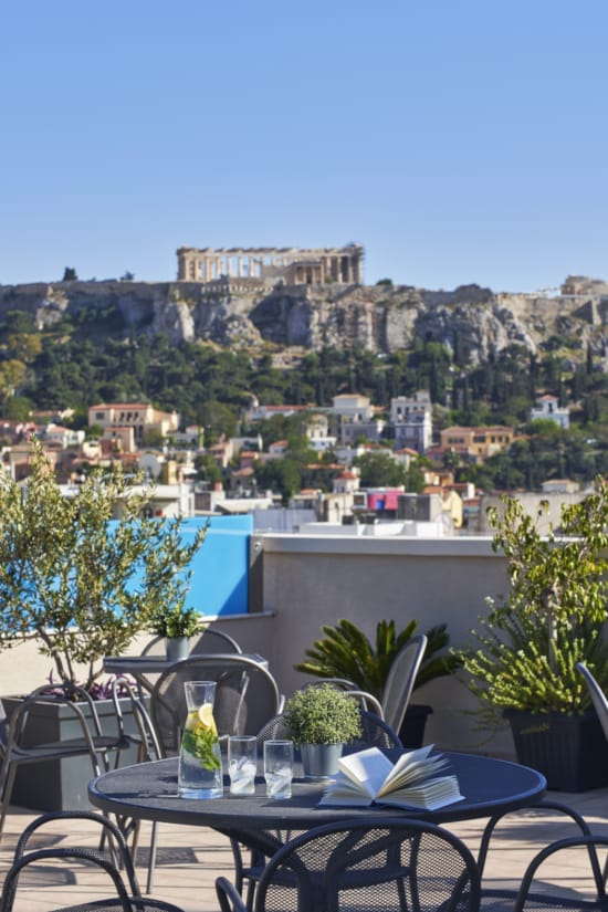 a table with glasses and plates on it with a city in the background