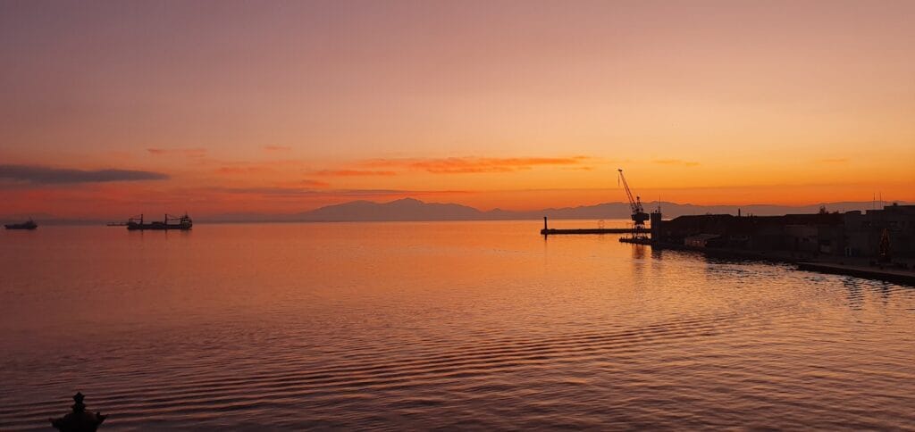 a body of water with boats in it and a sunset in the background