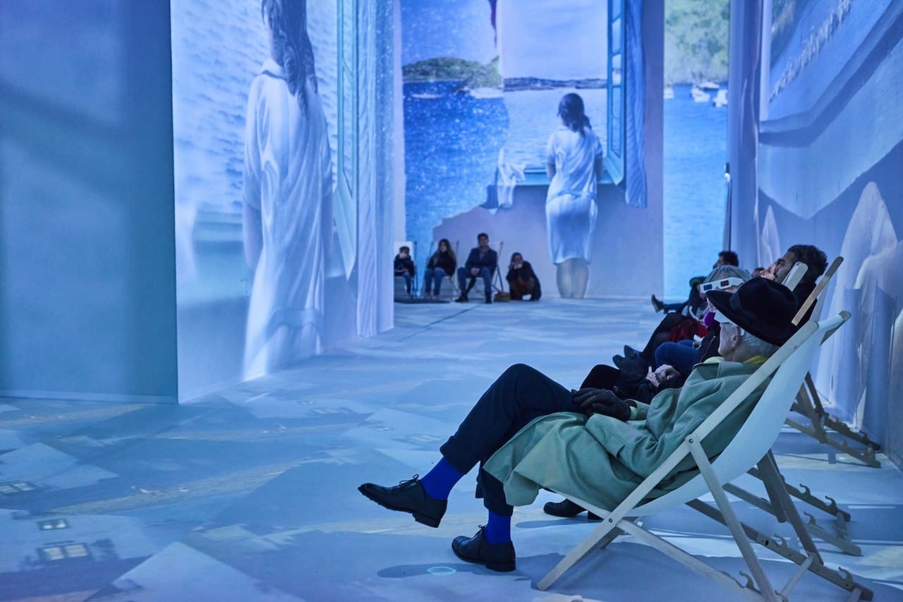 a woman in a white dress sitting on a chair in a room with a man in a white