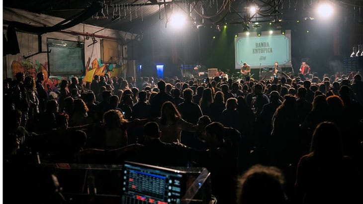 a large group of people in a room with a stage and a screen