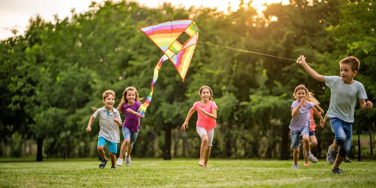 a group of kids running with a kite