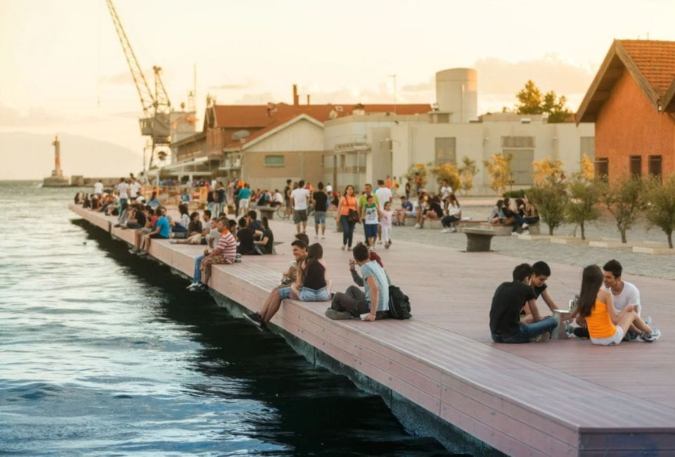 a group of people sitting on a dock by a body of water