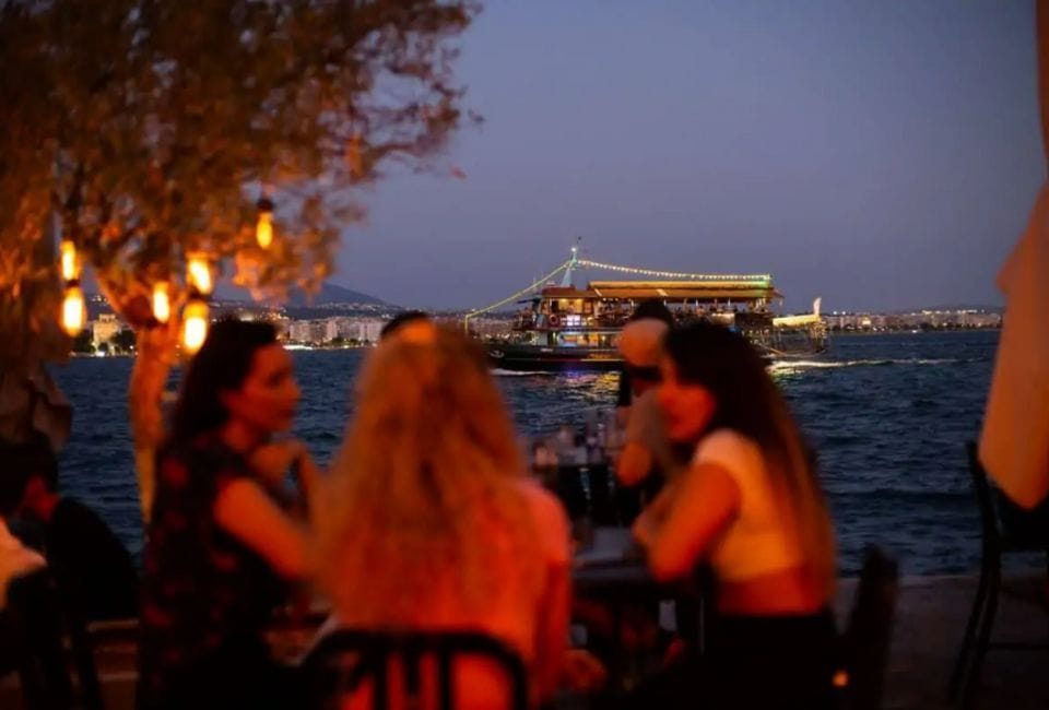 a group of people sitting at a table by a body of water