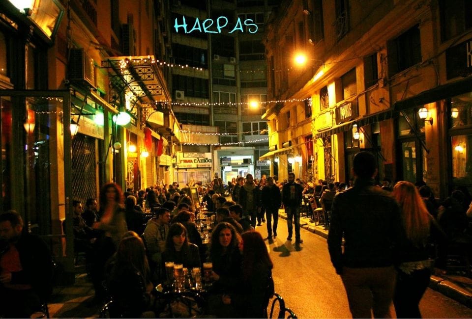 a group of people sitting at tables in a street at night