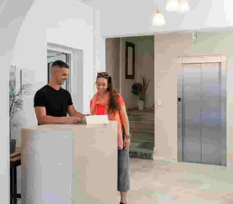 a man and woman standing at a counter in a room with a white door and a white wall
