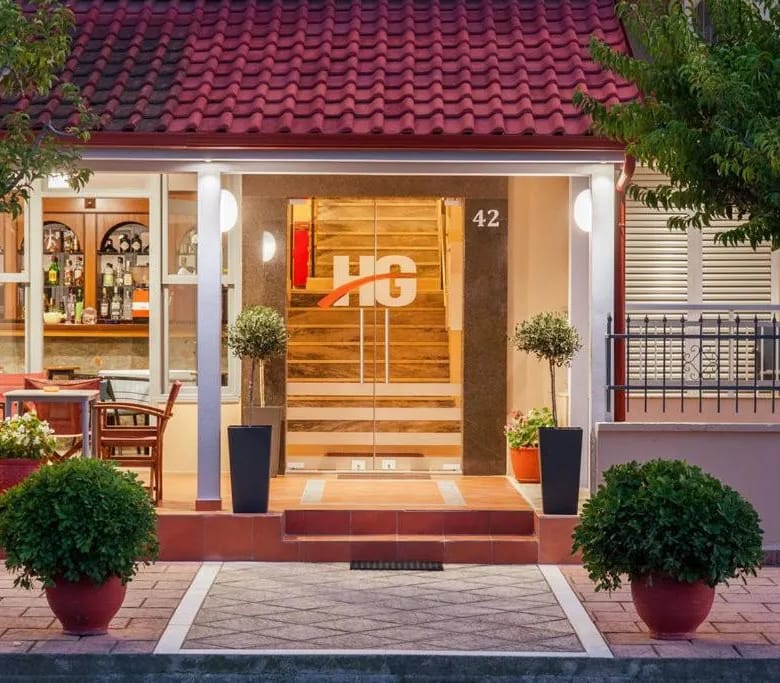 a building with a red roof and plants in front of it