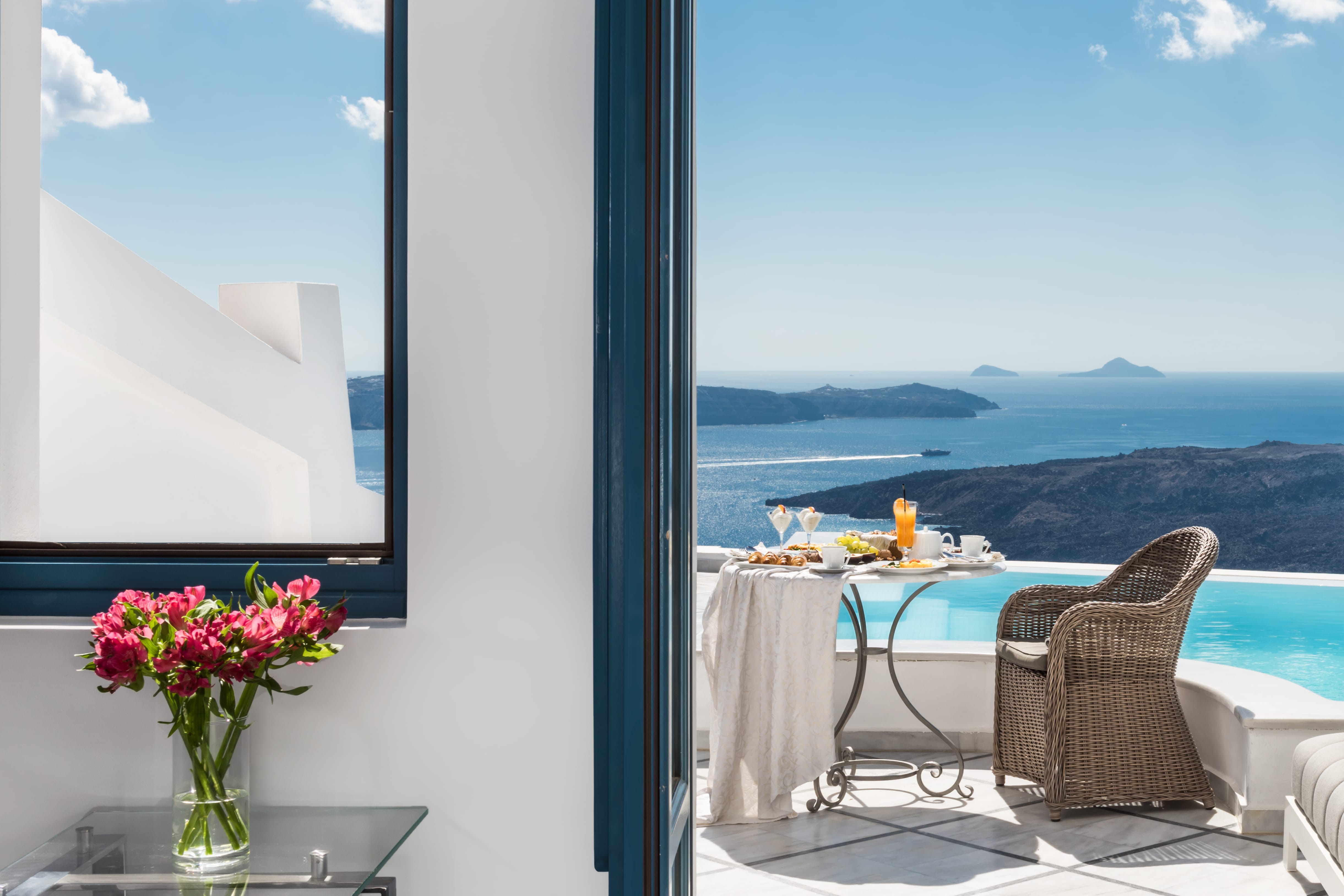 a table and chairs in a room with a view of the ocean