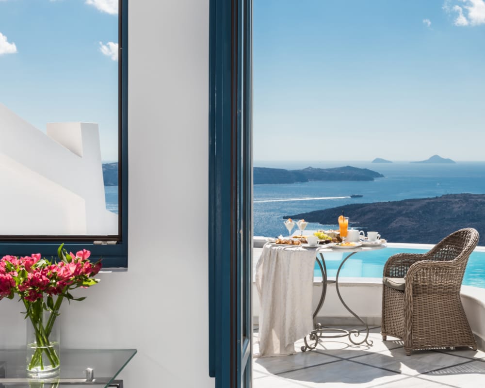 a table and chairs in a room with a view of the ocean