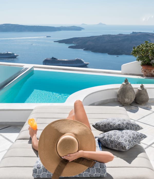 a hand holding a cup of coffee by a pool with a view of the ocean and islands