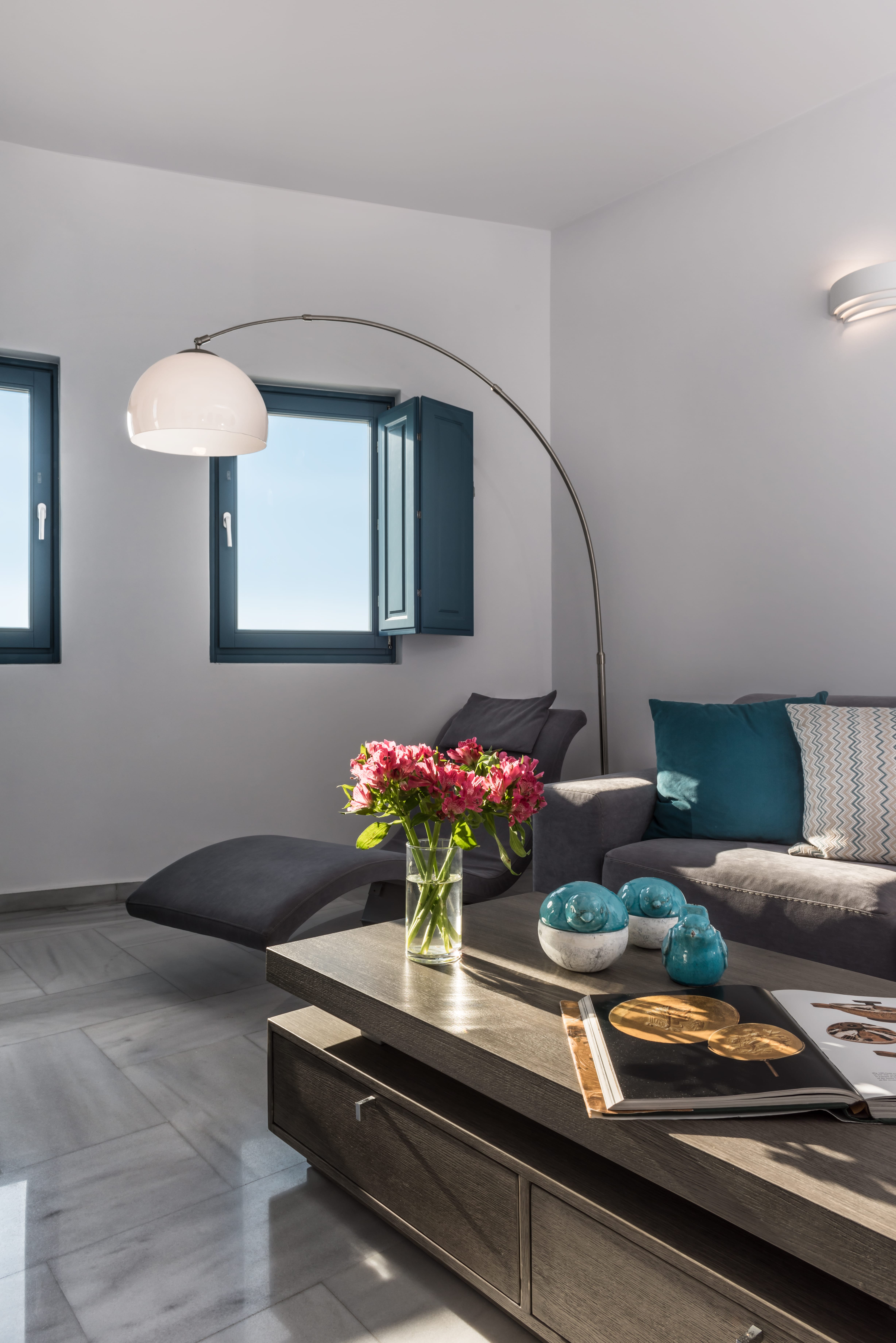 a living room with a glass coffee table and a vase of flowers