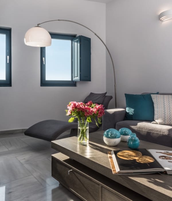 a living room with a glass coffee table and a vase of flowers