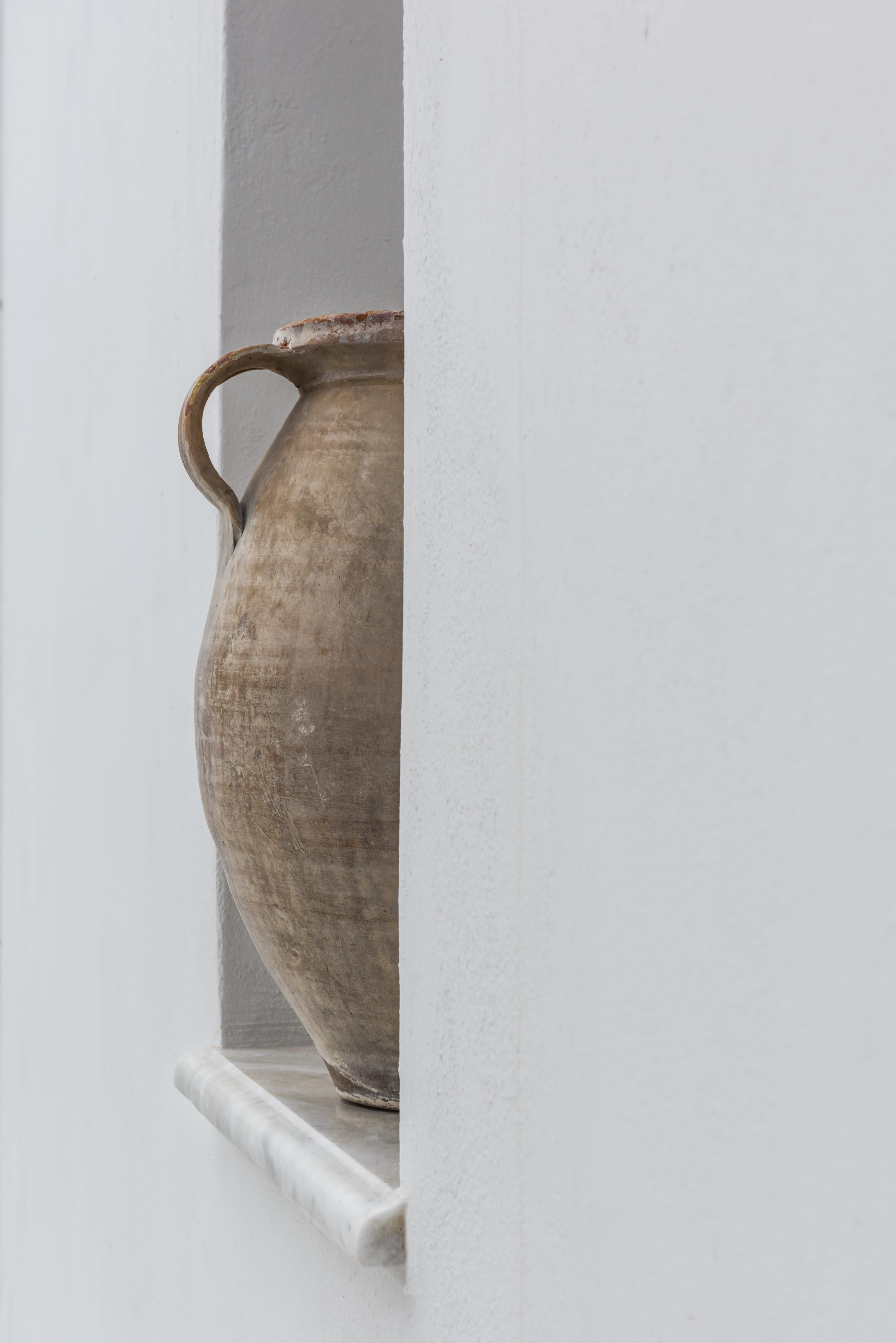 a brown vase on a white shelf