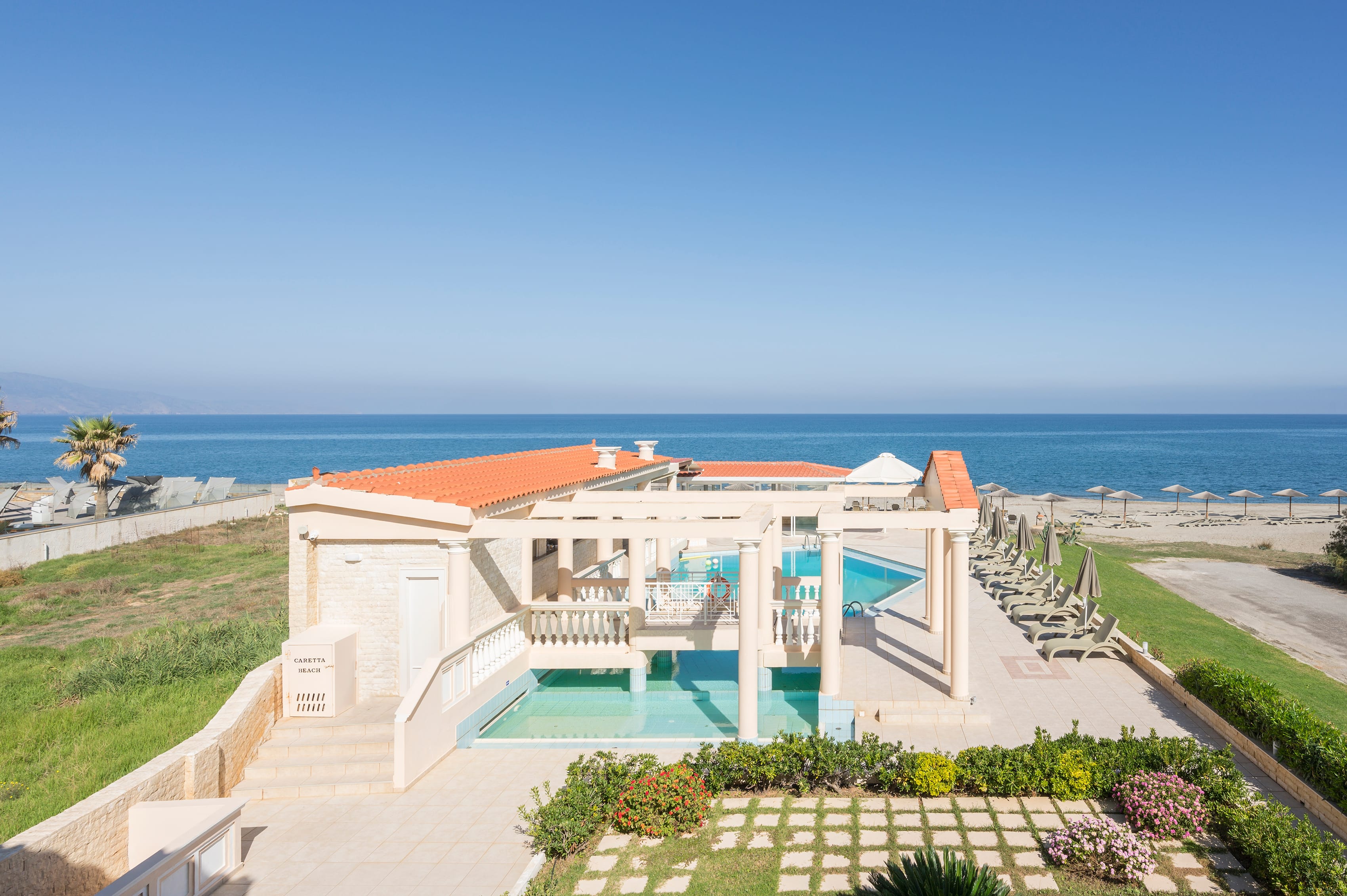 a house with a pool and a beach in the background