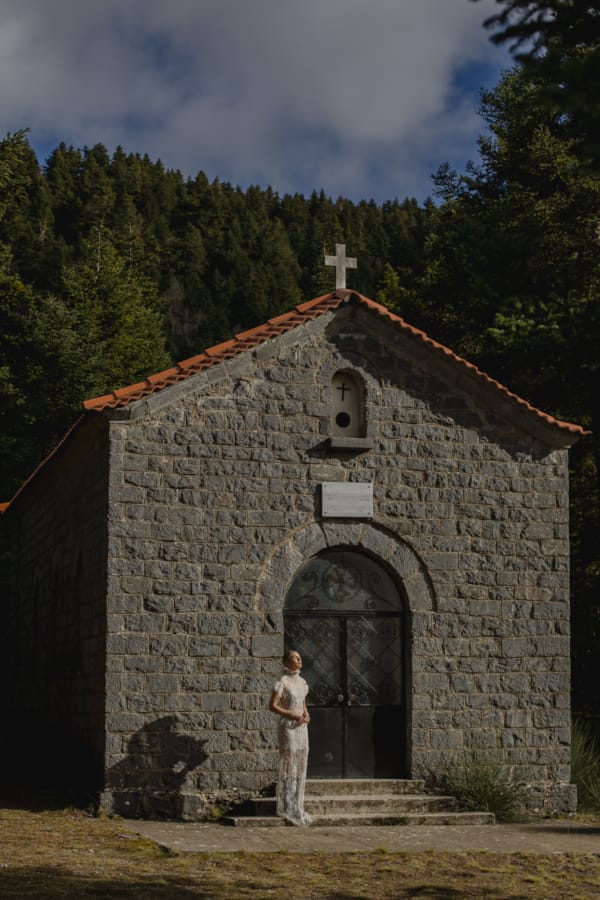 a person standing in front of a brick building with a cross on top