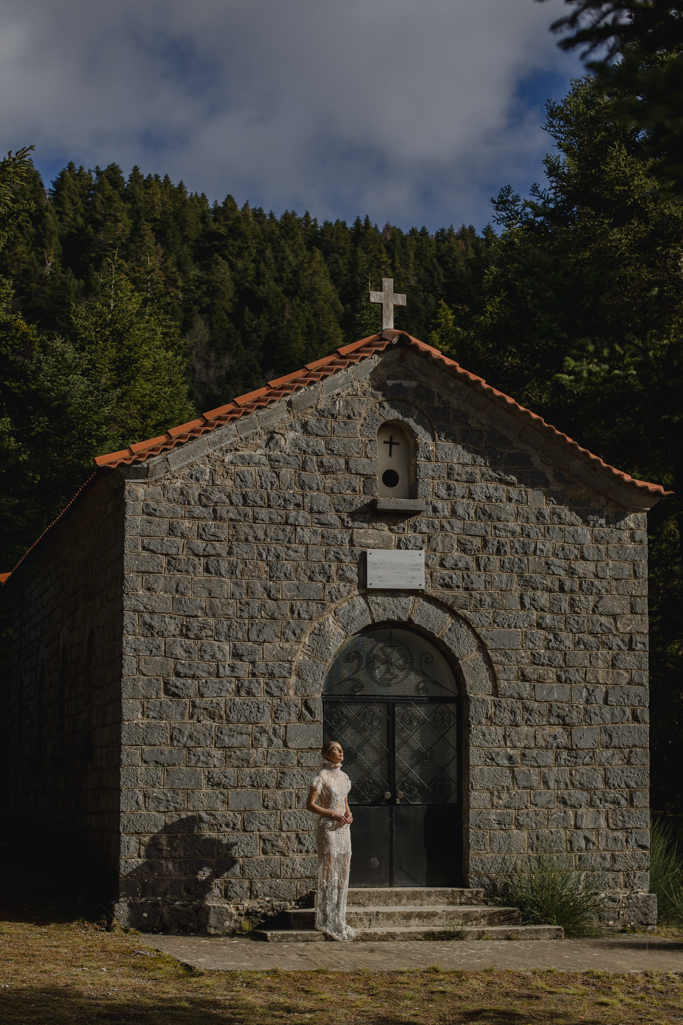 a person standing in front of a brick building with a cross on top