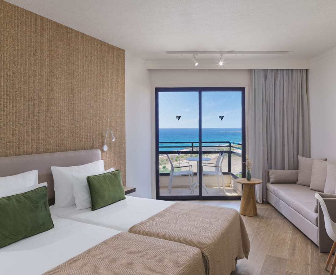 a room with two beds and a window overlooking the ocean