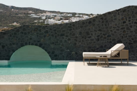 a pool and a lounge chair on a beach