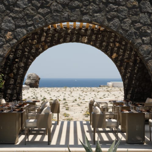 a patio with tables and chairs and a view of the ocean