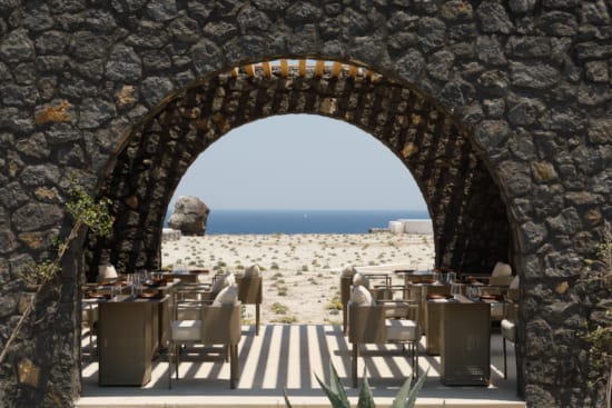 a patio with tables and chairs and a view of the ocean